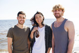 Cheerful guys looking at camera on background of seaside on summer weekend