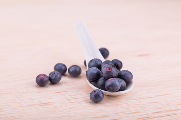 Organic blueberries scooped in spoon on wooden surface