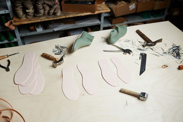 Handtools of shoemaker and workpieces on wooden workplace