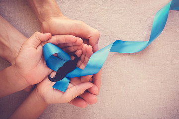 Adult and child hands holding Light blue ribbons with mustache , Prostate Cancer Awareness, Men...