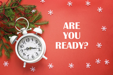 Christmas alarm clock with fir tree  branches  on red background. Are you ready for Christmas?