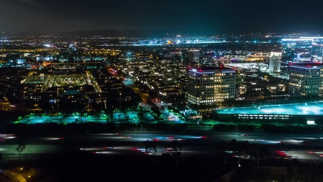 Aerial timelapse in motion or hyperlapse at night along the urban California I-405 interstate with cars, traffic and high-rise buildings below.