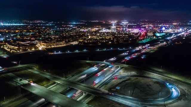 Urban aerial drone time lapse in motion or hyperlapse at night flying towards a highway with cars and traffic showing the on and off ramp circles indicative of the fast paced futuristic city lifestyle
