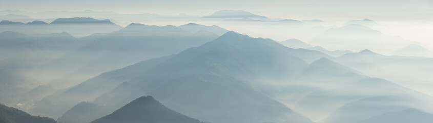 Morning landscape on hills and mountains with humidity in the air and pollution. Panorama from Linzone Mountain, Bergamo, Italy - obrazy, fototapety, plakaty