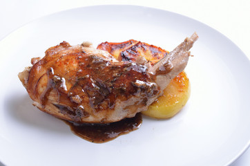 Sous Vide rabbit leg with sous and grilled apple on white plate.