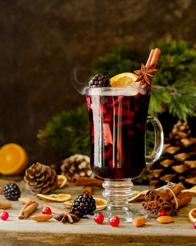 glass of hot mulled wine for the new year with ingredients for cooking, nuts and Christmas decorations