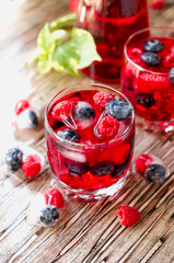 Summer berry lemonade with frozen berries on a wooden rustic table, selective focus