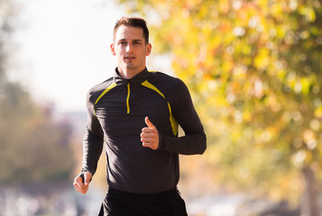 Naklejka premium Young man wearing sportswear and running in forest at mountain