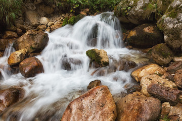 waterfall among rocks covered with green moss