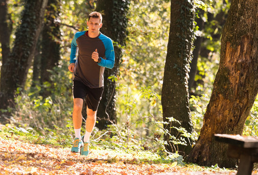 Young man wearing sportswear and running in forest at mountain