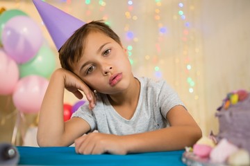 Boy sitting near a birthday cake at home