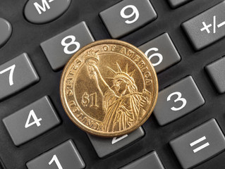 US one dollar coin on the calculator. Close up.