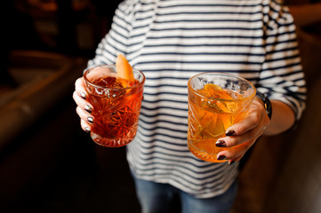 Woman in striped shirt holding glasses with fresh cocktails