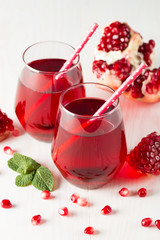 A glass of pomegranate juice with fresh pomegranate fruits on wooden table. Vitamins and minerals. Healthy drink concept.