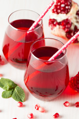 A glass of pomegranate juice with fresh pomegranate fruits on wooden table. Vitamins and minerals. Healthy drink concept.