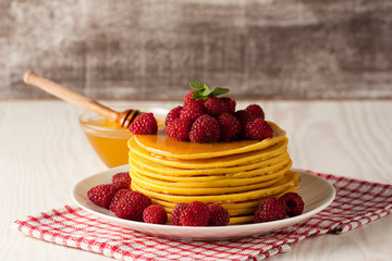 Fresh made delicious pancakes with berries, blackberries, raspberries, banana, honey and maple syrup. Healthy morning breakfast concept.