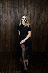 Fototapeta na wymiar Halloween skull make up girl wear in black against wooden wall at studio.