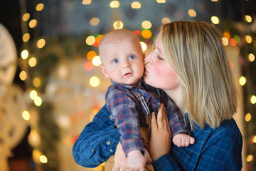 happy mother kisses her young son on the background of festive lights.