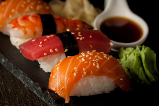 Sashimi and sushi rolls on a stone slatter. Sushi set with salmon, prawns, soy souce, wasabi and ginger. Traditional Japanese cuisine.