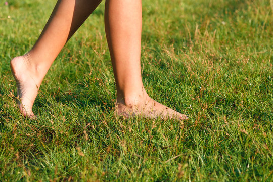 female walking on green grass barefoot