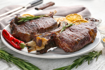 Plate with delicious grilled steaks on wooden table