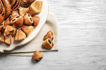 Tasty pastries with poppy seeds on wooden board