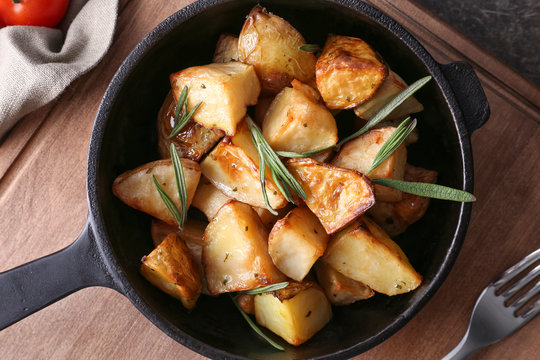 Delicious baked potatoes with rosemary in pan on table