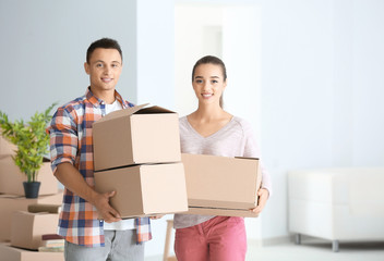 Happy young couple with moving boxes in their new apartment