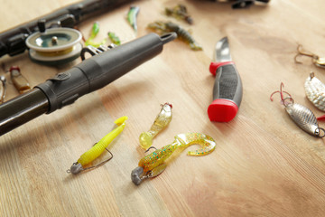 Spoon baits and fishing rod on wooden table