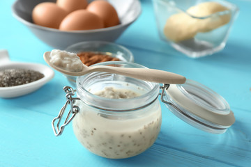 Fototapeta na wymiar Glass jar and spoon with chia seed pudding on color wooden background