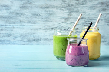 Jars with yummy smoothie on wooden background