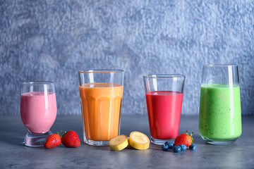 Glasses with different smoothies on grey background