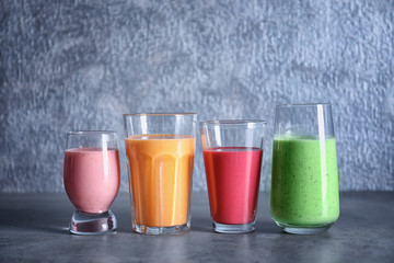 Glasses with different smoothies on grey background