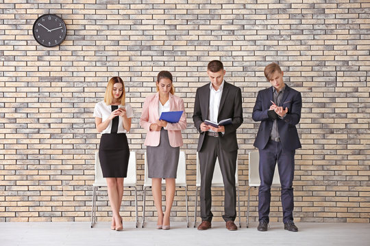 Group of people waiting for job interview on brick wall background