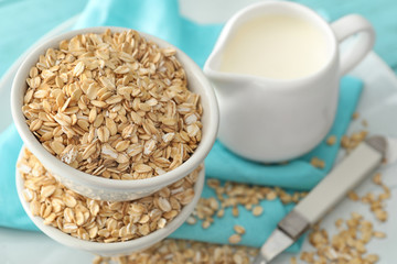 Bowls with oatmeal flakes and pitcher on fabric