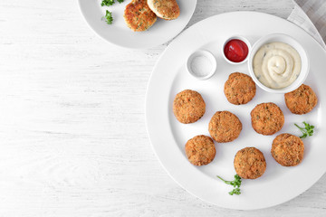 Plate with delicious salmon patties on table