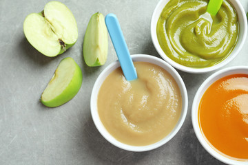 Bowls with baby food on grey background
