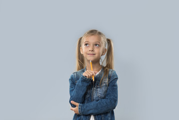 Beautiful Little Girl Hold Pencil Writing Thinking Happy Smiling Looking To Copy Space Isolated Over Gray Background