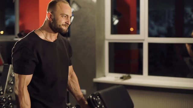 Strong man doing exercise with dumbbells in studio. 4K