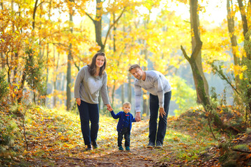 Obraz premium happy family walking in beautiful autumn park at sunset.