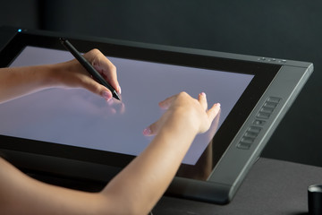 Woman hand drawing on professional graphic tablet. Black background