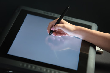 Woman hand drawing on professional graphic tablet. Black background