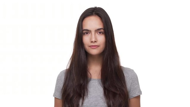 portrait of calm young woman with long dark hair opening eyes and looking at camera isolated over white background closeup. Concept of emotions