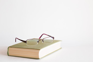 Old book and reading glasses on the table. Education concept. Empty place for a text. Mock up for different ideas.