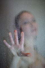 The palm of a woman on the glass shower enclosure