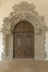 Old, antique, wooden door surrounded by ornamental wall.