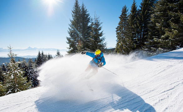 Professional skier skiing downhill in the Carpathians mountains. Blue sky and winter forest on the background