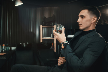 customer with glass of whiskey/ A stylish man in a suit enjoys a whiskey in Barbershop