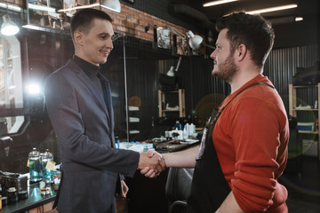 handshake/ The client shakes hands with barber in barbershop