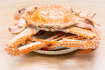 steamed horse crab or blue crab in dish on wood table background (Portunus pelagicus)